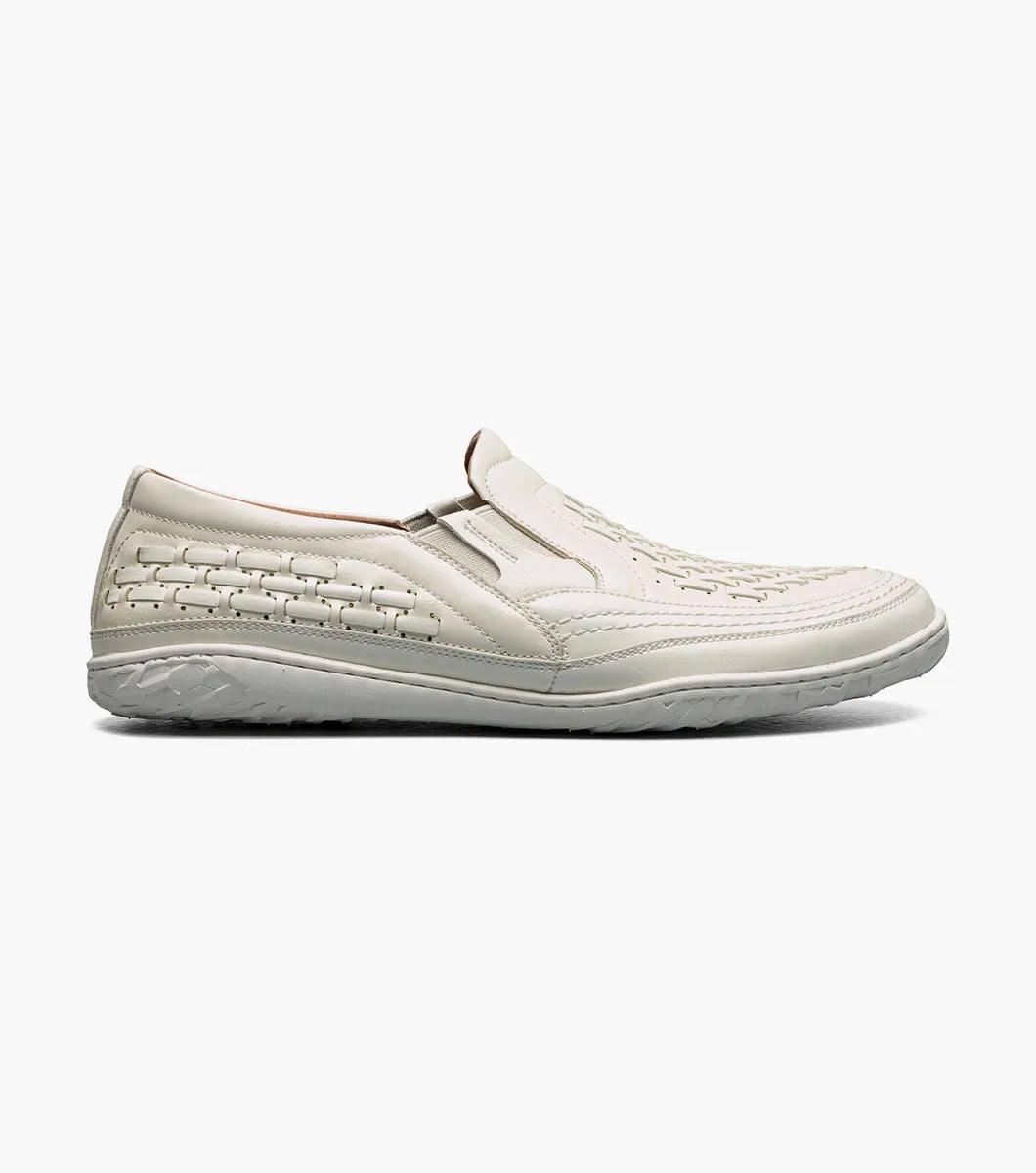The Stacy Adams Ithaca Moc Toe Slip On in white features woven detailing, a textured sole, elastic side panels for easy wear, and a cushioned memory foam footbed for comfort.