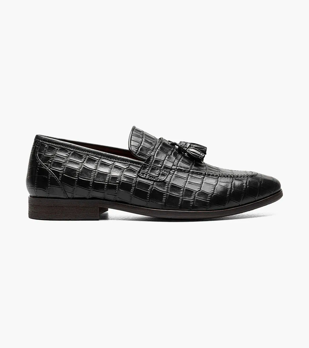 STACY ADAMS Franz Moc Toe Tassel Slip On loafer in black crocodile print leather features a slip-on design with tassel detail, a RedZone footbed for enhanced comfort, and a low brown heel. Shown on a plain white background.