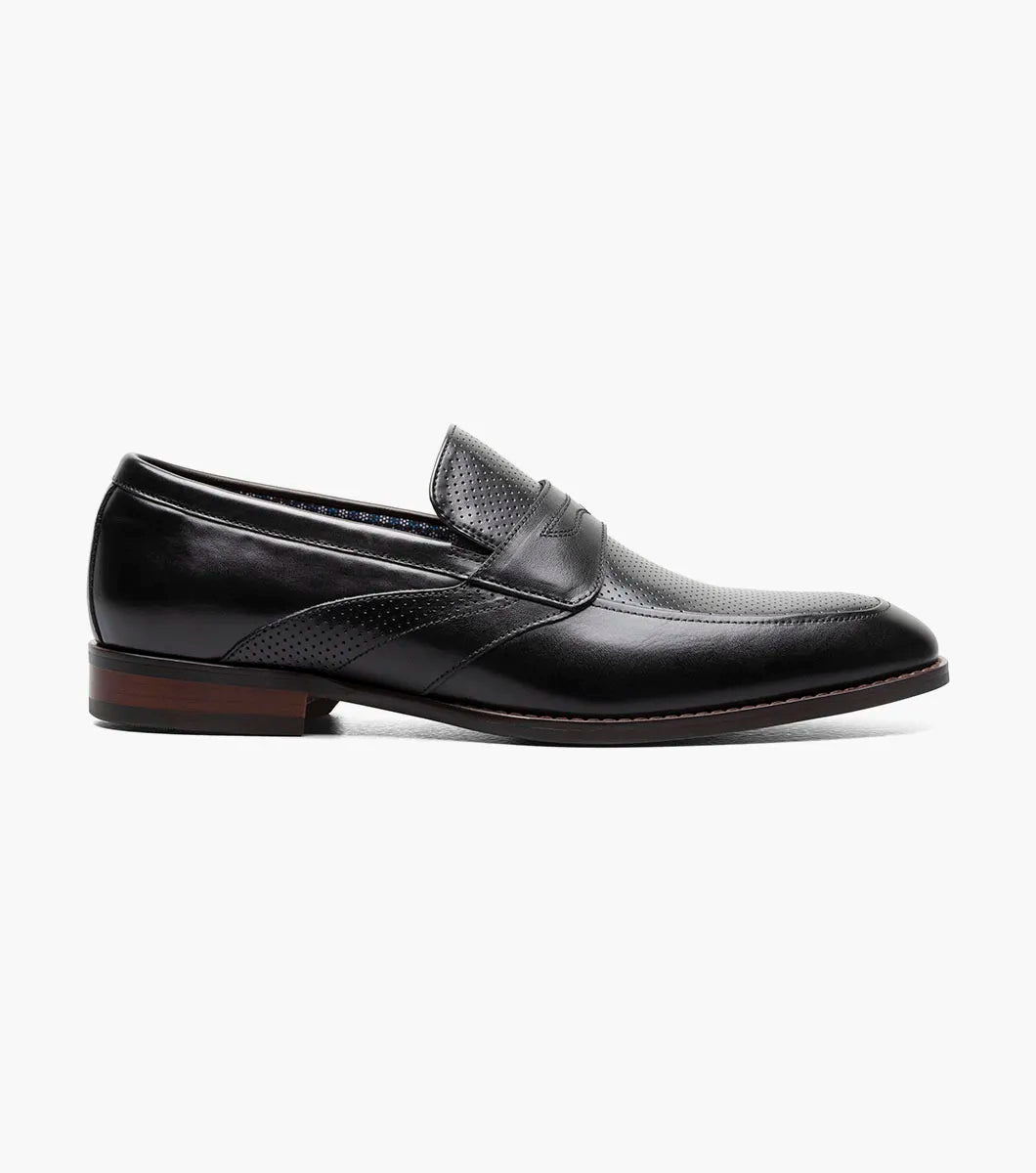The STACY ADAMS Karnes Moc Toe Penny Slip On in black (25591-001) features an orthotic insole with a molded heel cup, anatomical arch support, cushioned heel pod, and durable rubber outsole. Displayed on a white background with labeled features.