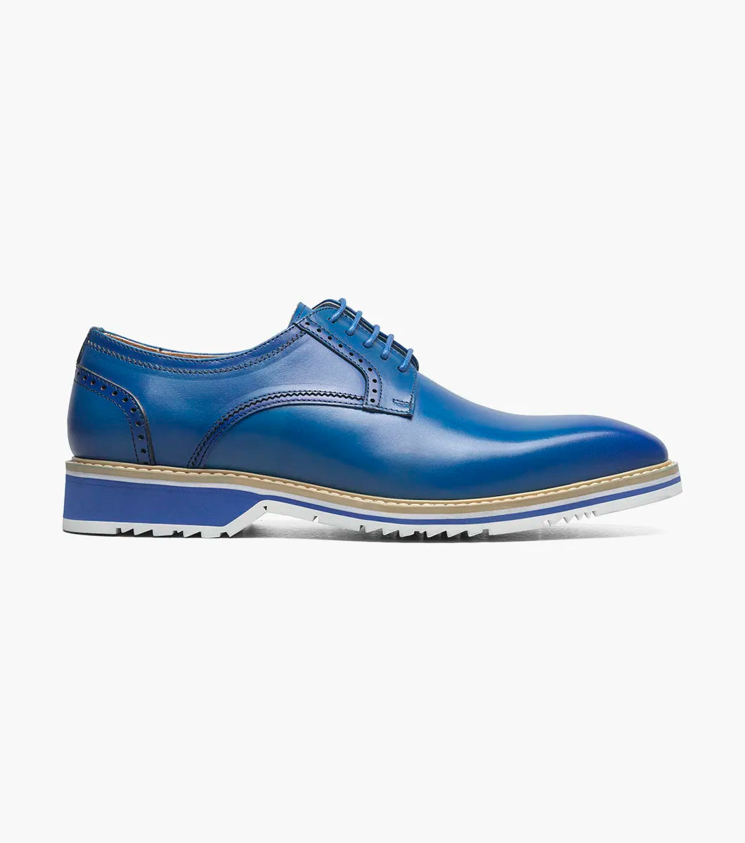 The Stacy Adams Barringer Plain Toe Oxford in blue features a leather upper with laces, a tan and white layered sole, durable rubber outsole, and subtle stitching details, shown in side view against a white background.