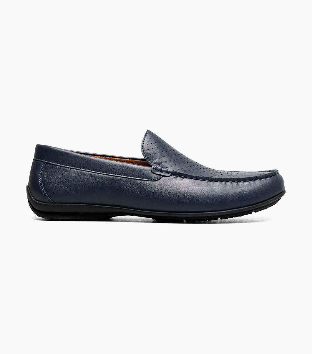The STACY ADAMS Conroy Moc Toe Perf Slip On (Navy, 25702-410) features a perforated leather upper, cushioned footbed, and black sole, shown in side profile against a plain white background.