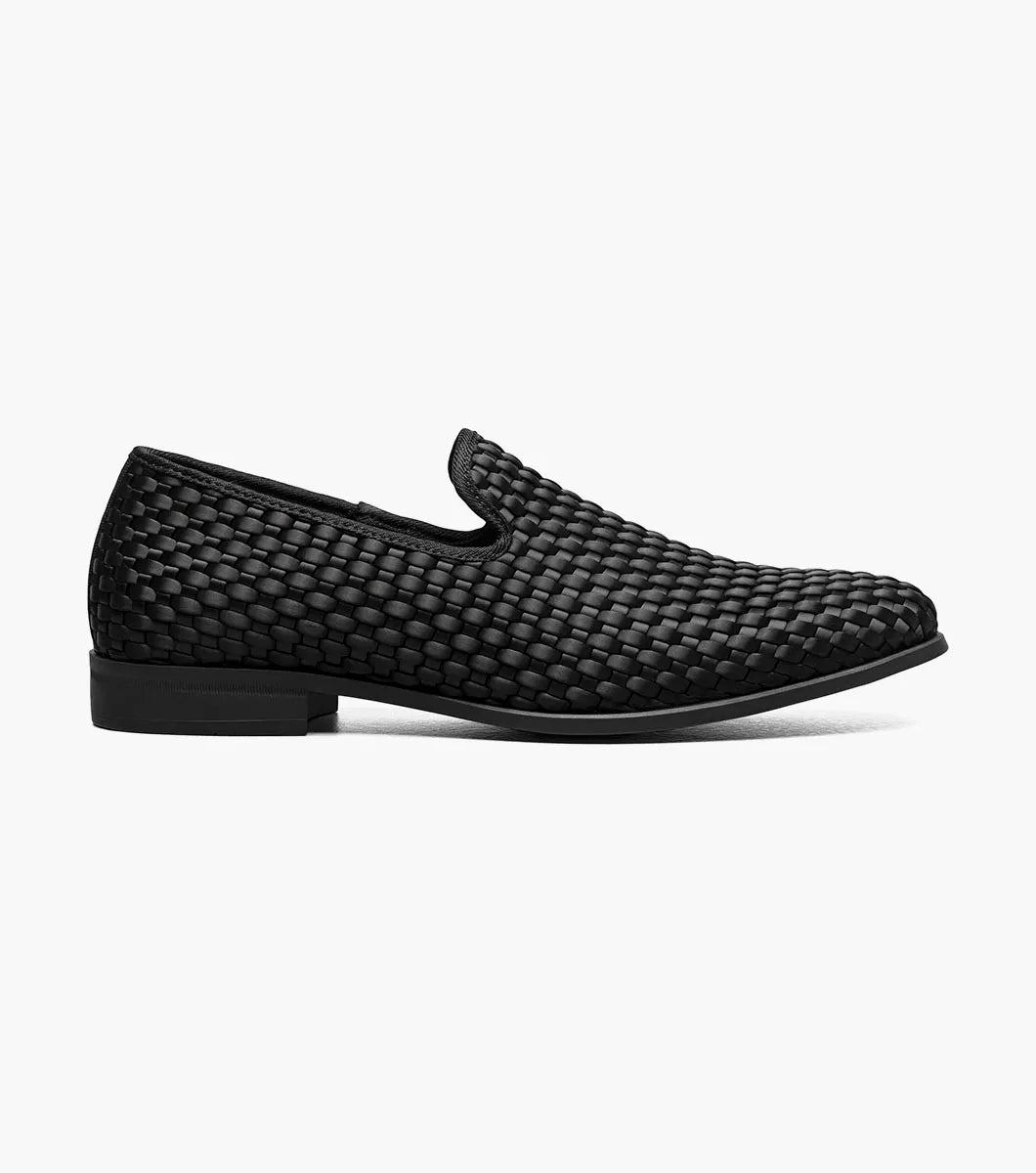 The STACY ADAMS Swenson Woven Slip On in black (25697-001) is a woven leather loafer featuring a low heel and cushioned insole, shown against a white background.