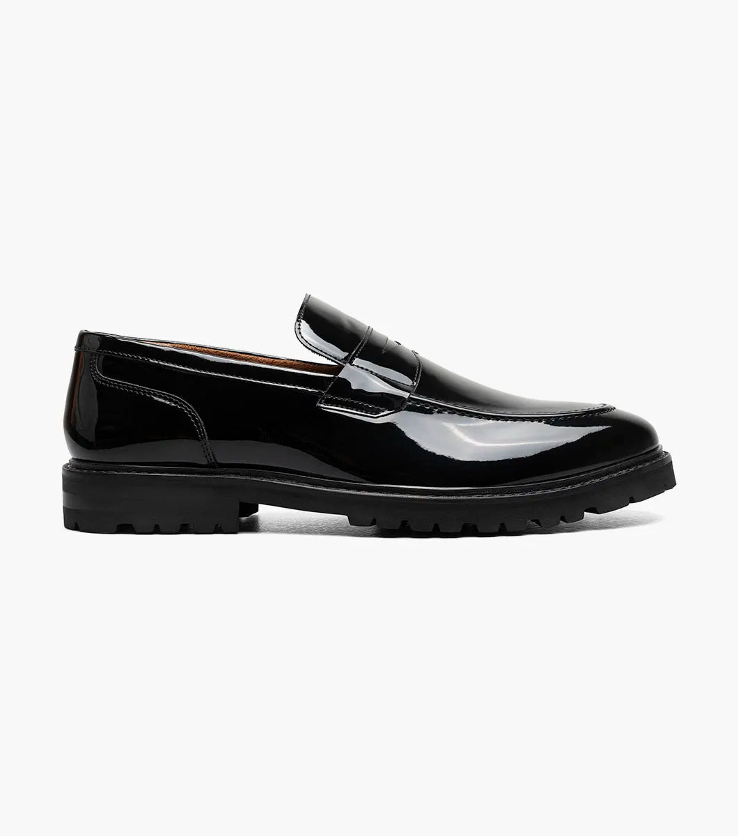 The Stacy Adams Hazelton Moc Toe Penny Slip On (25736-004) in black patent leather features a low heel, thick rubber sole, and RedZone footbed, shown on a white background.