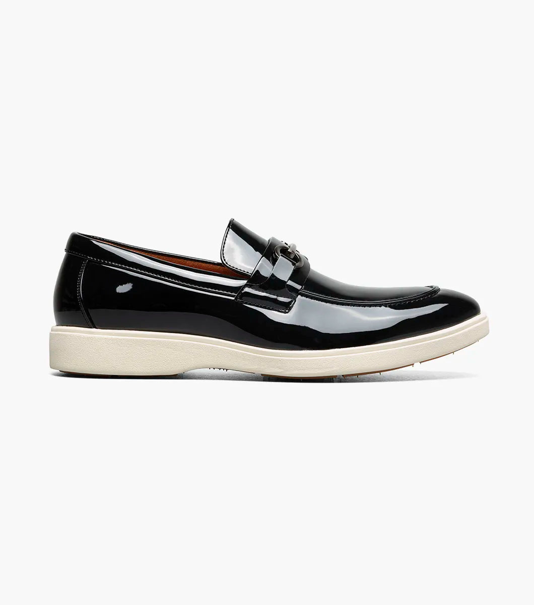 The Stacy Adams Slayton Moc Toe Bit Slip On (25710-004) is a black patent leather loafer with a white sole, displayed in side profile against a plain white background.