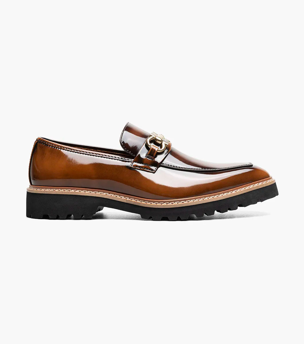 Introducing the Stacy Adams Carabello Moc Toe Bit Slip On in Brown Multi (style 25804-249), this loafer features brown leather with a shiny finish, a gold metal bit detail on the front, contrast stitching, and a black rubber sole. Designed by STACY ADAMS, it offers all-day comfort thanks to its cushioned Memory Foam insole.