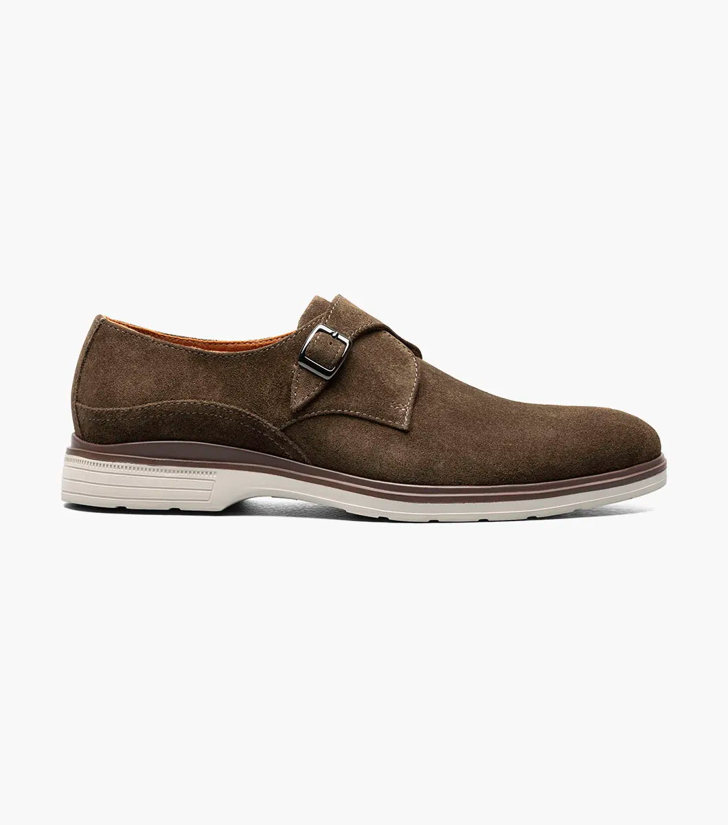 The STACY ADAMS Taylen Plain Toe Monk Strap (Brown Suede, 25589-245) features men's suede leather, a single side buckle, anatomical arch support, low heel, and a light rubber sole, displayed on a white background.