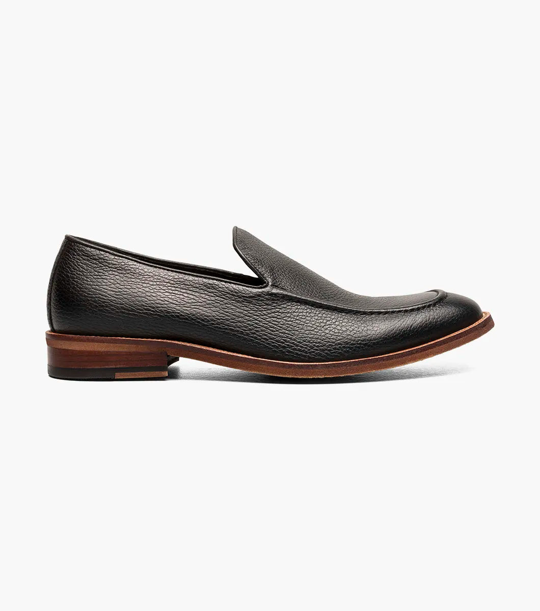The Stacy Adams Prentice Moc Toe Slip On (25649-007) features black tumbled leather, a textured finish, brown wooden heel, and thin brown sole; shown on a white background.