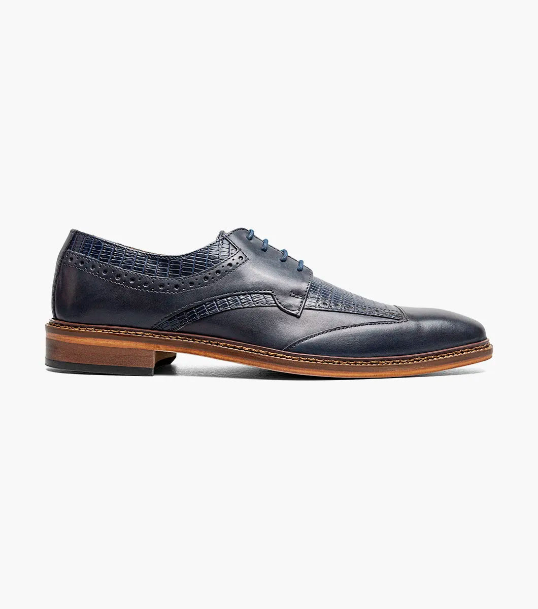 The STACY ADAMS Gambetta Modified Cap Toe Oxford (Navy, 25780-410) is a navy blue leather dress shoe featuring a textured pattern, brown sole, RedZone footbed, and lace-up closure, displayed on a white background.