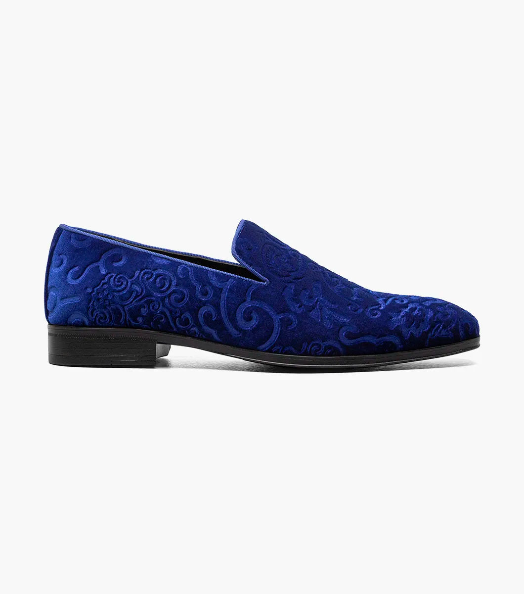 The STACY ADAMS Saunders Debossed Velour Slip On in Royal features a blue velour upper, low heel, intricate swirl embroidery, and a memory foam footbed. Shown in side profile against a white background. Style number: 25581-432.