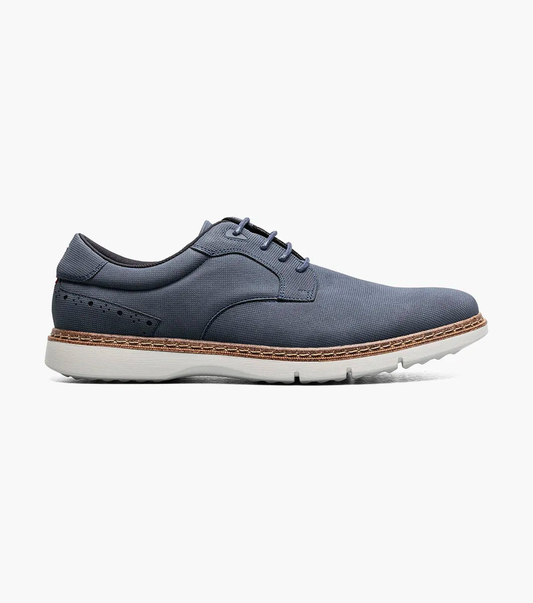 The STACY ADAMS Skyler Plain Toe Oxford in navy (style 21532-410) is a casual lace-up shoe crafted from man-made suede, featuring a white sole, brown stitching along the edge, subtle side perforation details, and a cushioned insole for enhanced comfort.