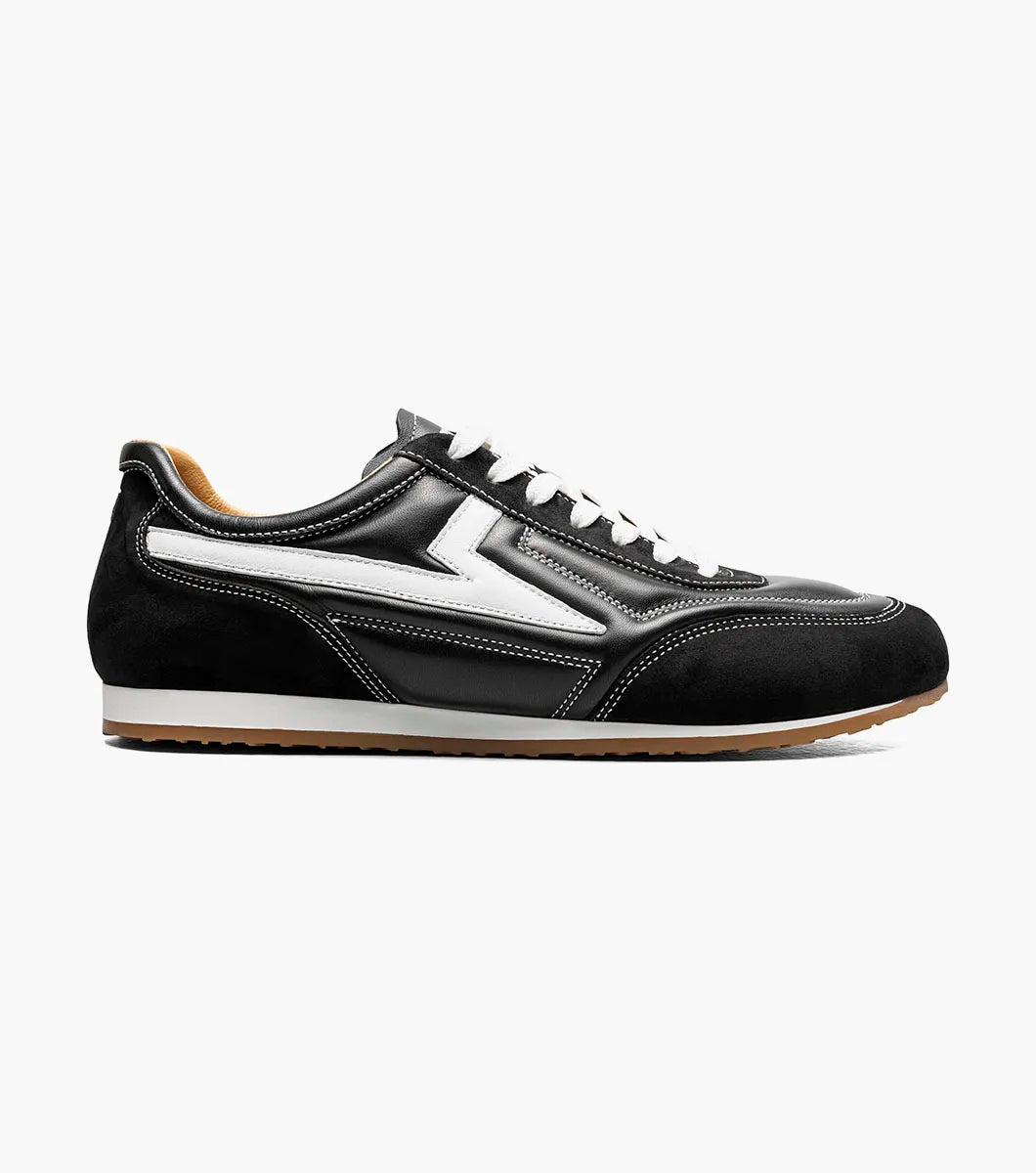 The Stacy Adams - Action 150 Sporty Lace Up sneaker (style 25797-001) is a black, low-top shoe featuring white laces, sporty lace-up design, distinctive white side detailing, and a brown rubber sole. It is shown in a side profile view on a plain white background.
