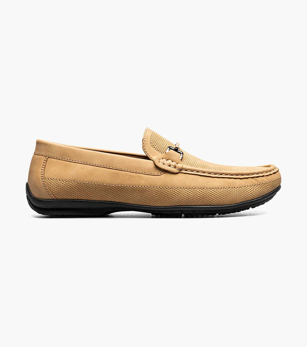 The Stacy Adams Colton Moc Toe Bit Slip On in khaki features a stitched moc toe, metal bit detail, black rubber sole, multicolored striped lining, and cushioned footbed for all-day comfort.