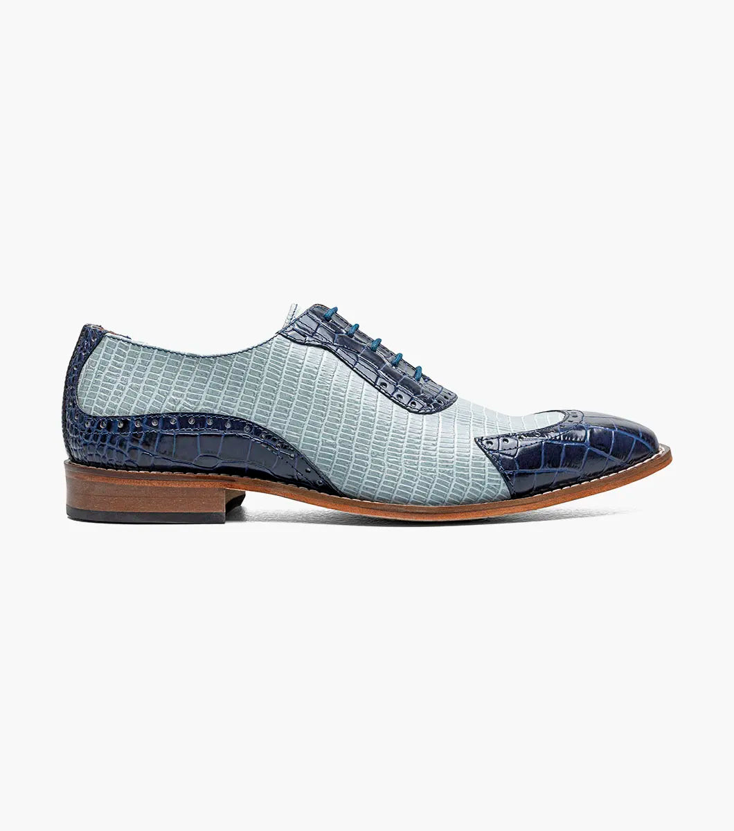 The Stacy Adams Tarango Modified Cap Toe Oxford in Dark Blue Multi features pointed toes, gray and blue crocodile print leather, and a low wooden heel—ideal for formal shoe enthusiasts.