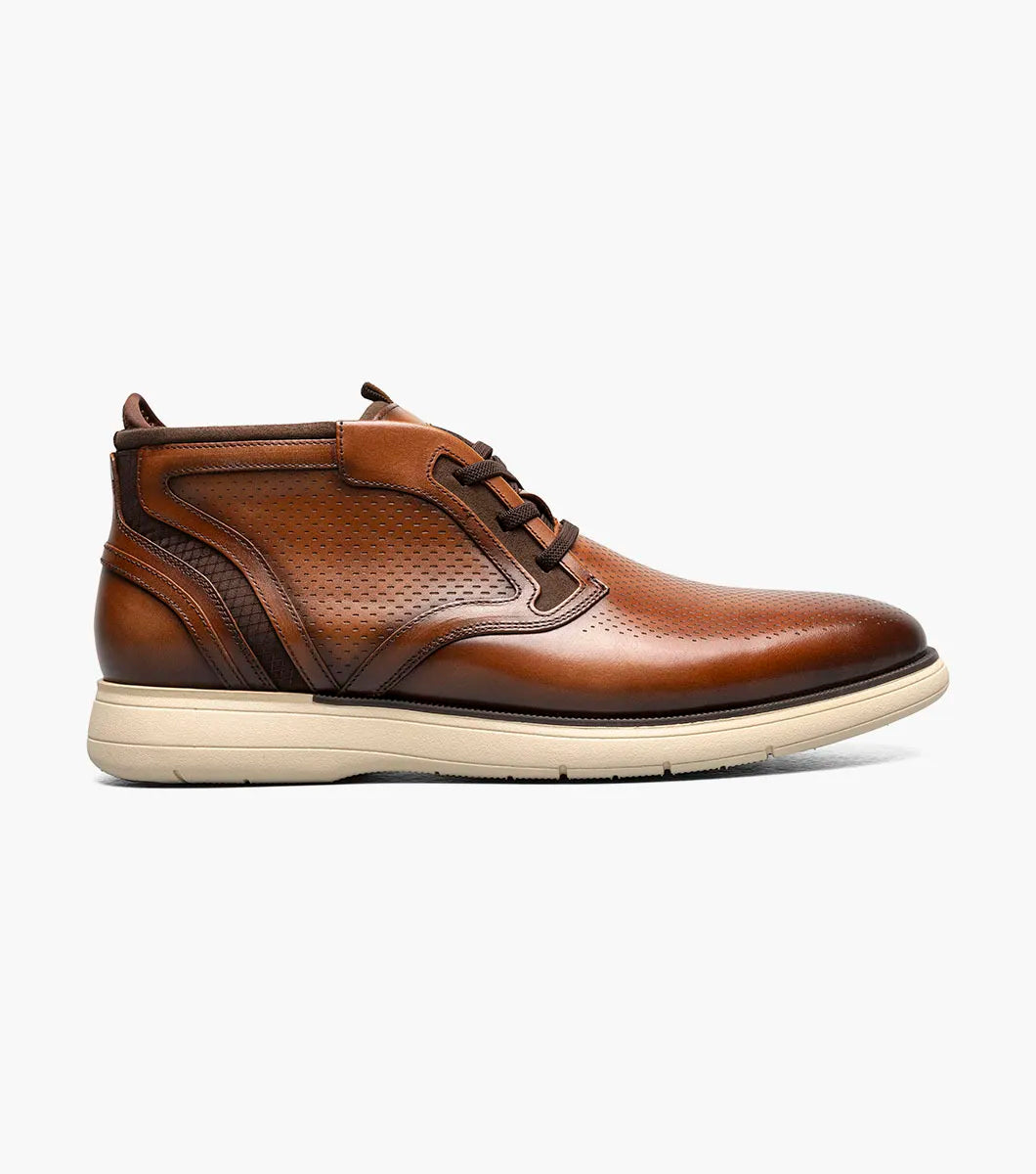 The Stacy Adams Eastmont Plain Toe Elastic Lace Chukka Boot in cognac features a perforated design, light tan rubber sole, and anatomical arch support for all-day comfort, shown on a white background.