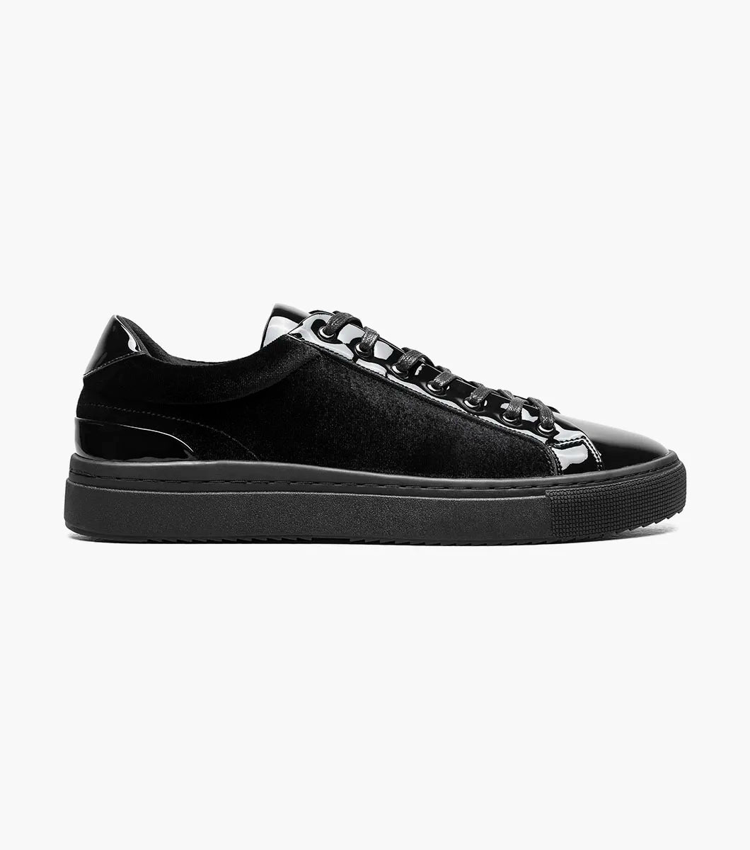 The Stacy Adams Dante Lace To Toe Sneaker in Black Smooth (Style 25806-005) features glossy patent leather and suede paneling, black laces, and a black rubber sole. Displayed on a white background, this STACY ADAMS low-top sneaker offers a sleek lace-to-toe design.