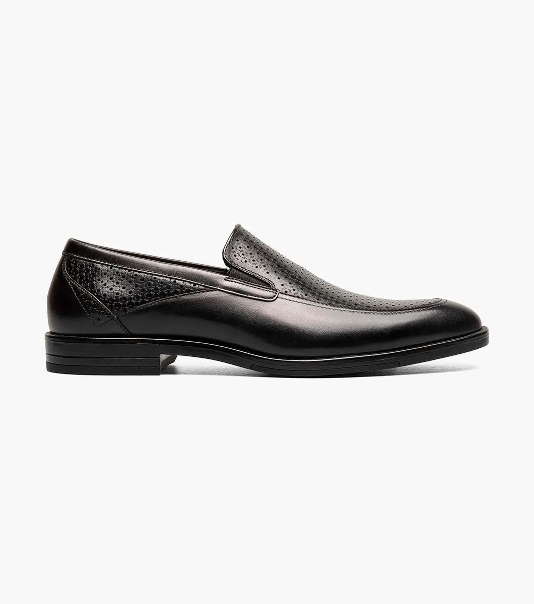The Stacy Adams Aiden Moc Toe Slip On (25655-001) in black features a genuine leather upper with textured perforation, anatomical arch support, and a low heel. Displayed on a white background.