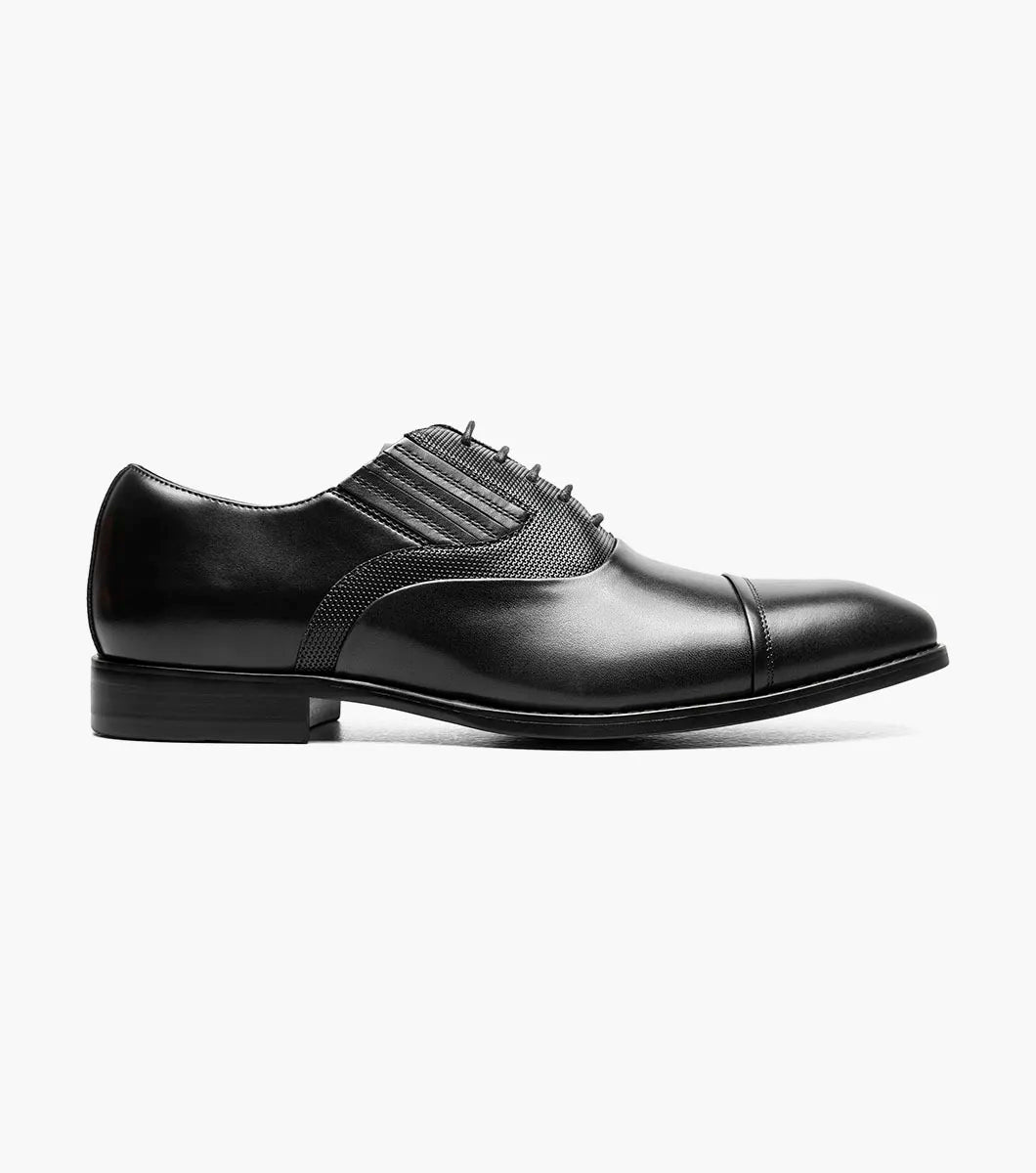 The STACY ADAMS Lucas Cap Toe Oxford (25766-001) is a black leather men's dress shoe with textured side panels, black laces, and a supportive RedZone footbed, shown on a plain white background.