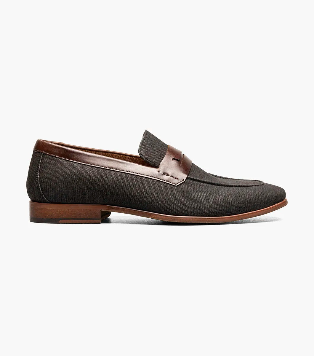 The STACY ADAMS Gill Moc Toe Saddle Slip On (25651-009) is a black multi men’s loafer with a leather upper accent, low heel, RedZone footbed, and rounded toe, shown on a white background.