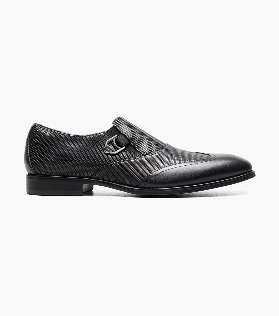 The STACY ADAMS Lockwood Wingtip Ornament Slip On in black (25767-001) features a textured upper, wingtip design, and is displayed on a white background.