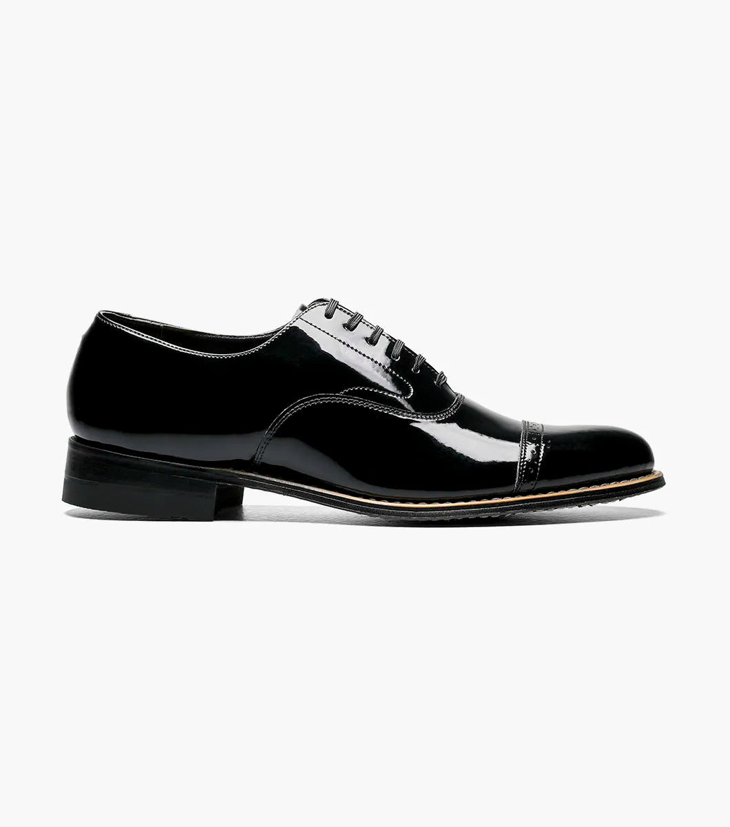The Stacy Adams Concorde Cap Toe Oxford (Style 11003-01) features a black patent leather upper, cap toe, black laces, low heel, and stitching detail. Shown in side profile against a white background. Brand: STACY ADAMS.