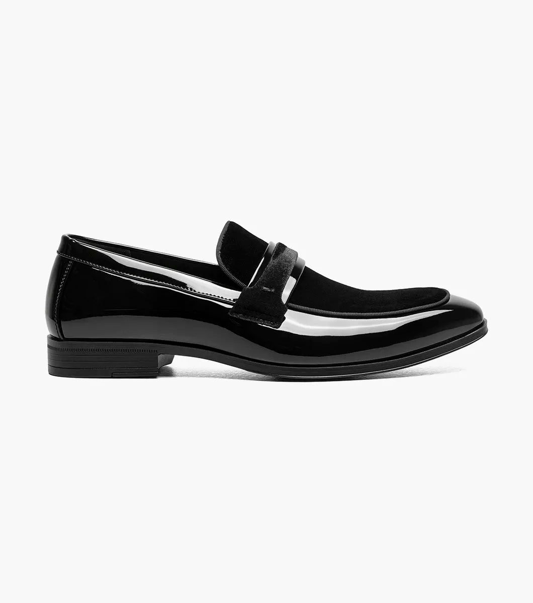 The STACY ADAMS Spratley Moc Toe Saddle Slip On in black features patent leather, a low heel, velvety strap detail, memory foam cushioning, and a slightly pointed toe, shown on a white background.