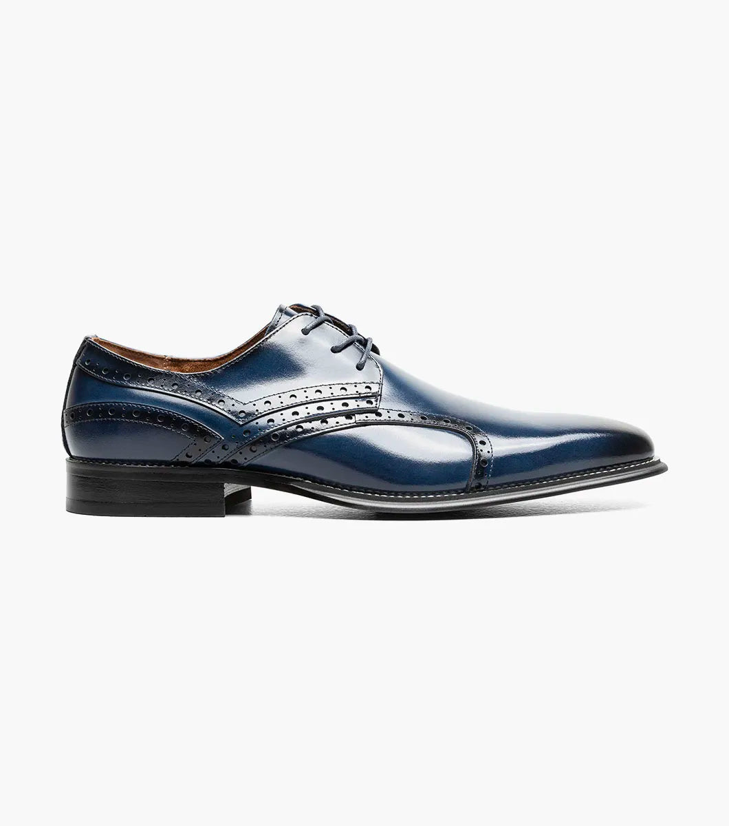 The Stacy Adams Alexander Plain Toe Oxford in Cobalt (style 25791-435) is a single shiny navy blue calf leather dress shoe by STACY ADAMS, featuring decorative perforations, laces, a memory foam insole, and a black sole, displayed against a white background.