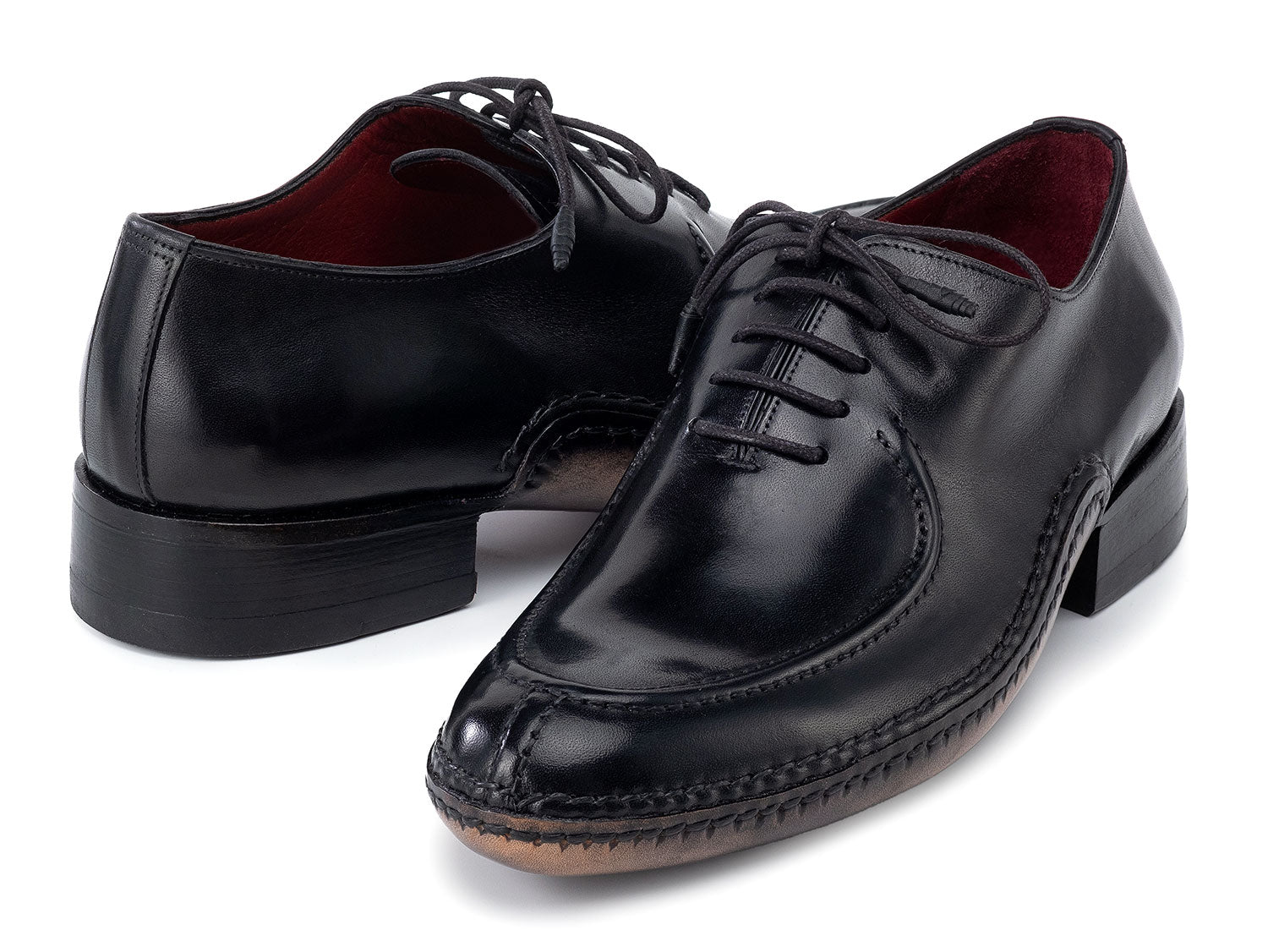 The Paul Parkman Opanka Stitched Men's Split-Toe Black Leather Oxford Shoes (054-BLK) are shown on a white background, one upright and the other leaning, both crafted from hand-painted leather with laces.