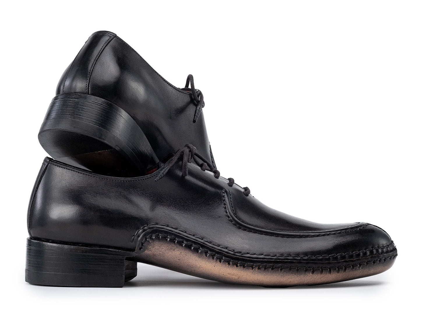 The Paul Parkman Opanka Stitched Men's Split-Toe Black Leather Oxford Shoes (054-BLK) are shown on a white background, one upright and the other leaning, both crafted from hand-painted leather with laces.