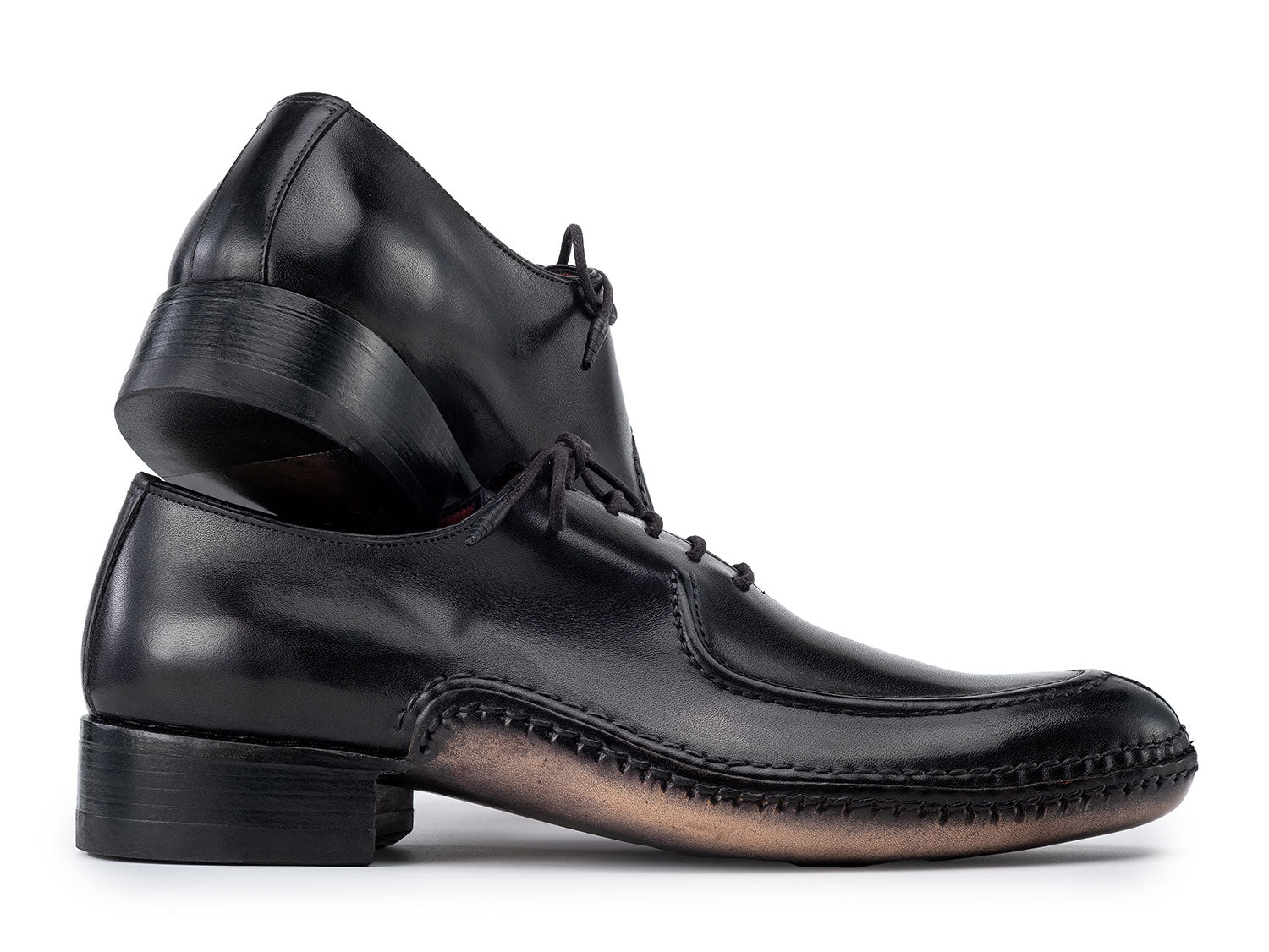 The Paul Parkman Opanka Stitched Men's Split-Toe Black Leather Oxford Shoes (054-BLK) are shown on a white background, one upright and the other leaning, both crafted from hand-painted leather with laces.