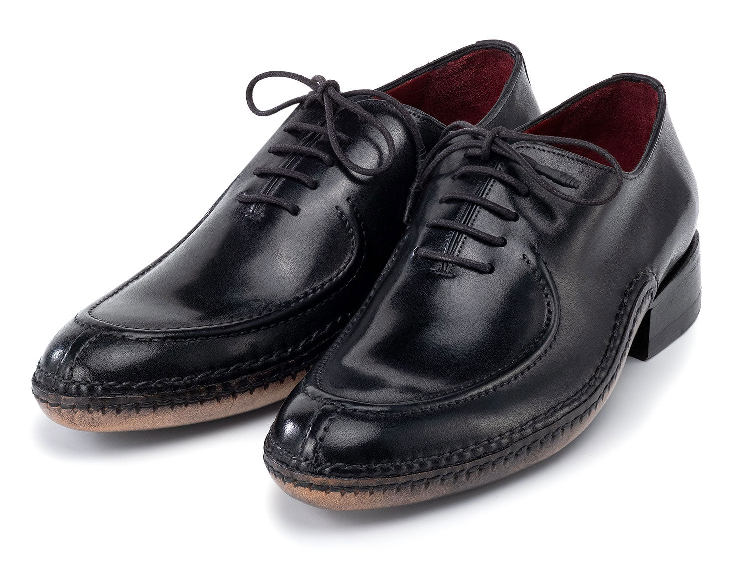 The Paul Parkman Opanka Stitched Men's Split-Toe Black Leather Oxford Shoes (054-BLK) are shown on a white background, one upright and the other leaning, both crafted from hand-painted leather with laces.