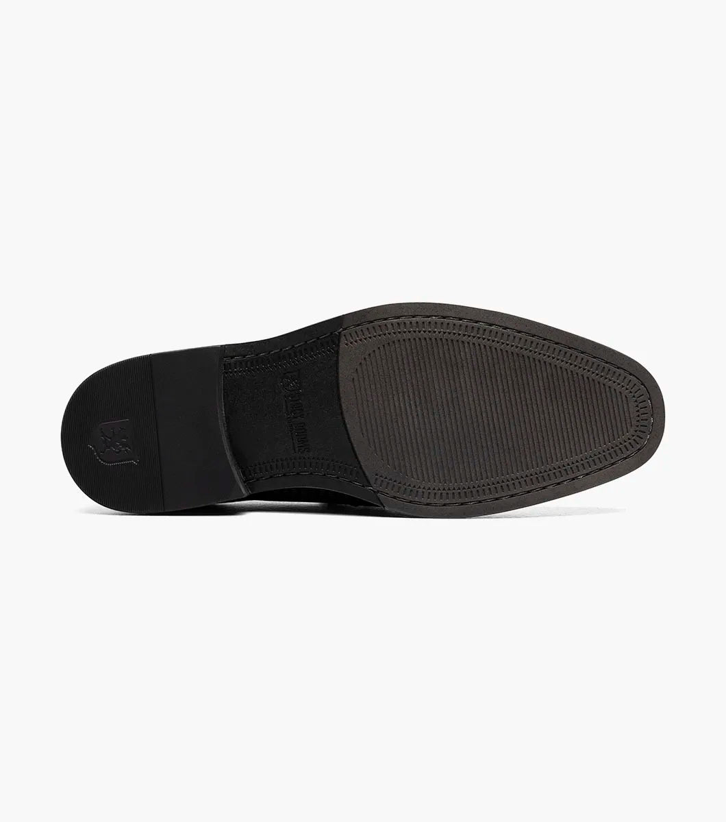 The STACY ADAMS Madsen Moc Toe Bit Slip On (Black, 25672-001) features black leather, a textured pattern, low heel, metallic horsebit detail, and anatomical arch support for all-day comfort.