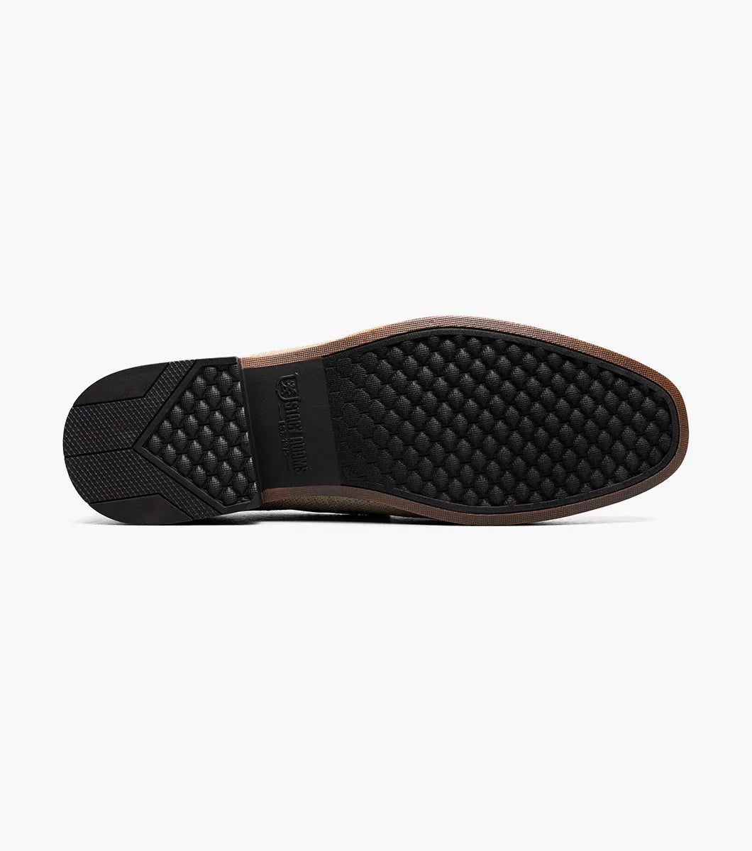 The Stacy Adams Ridgely Moc Toe Slip On (Natural) features a textured fabric upper, brown trim, anatomical arch support, and a low wooden heel for comfort, shown here on a white background.