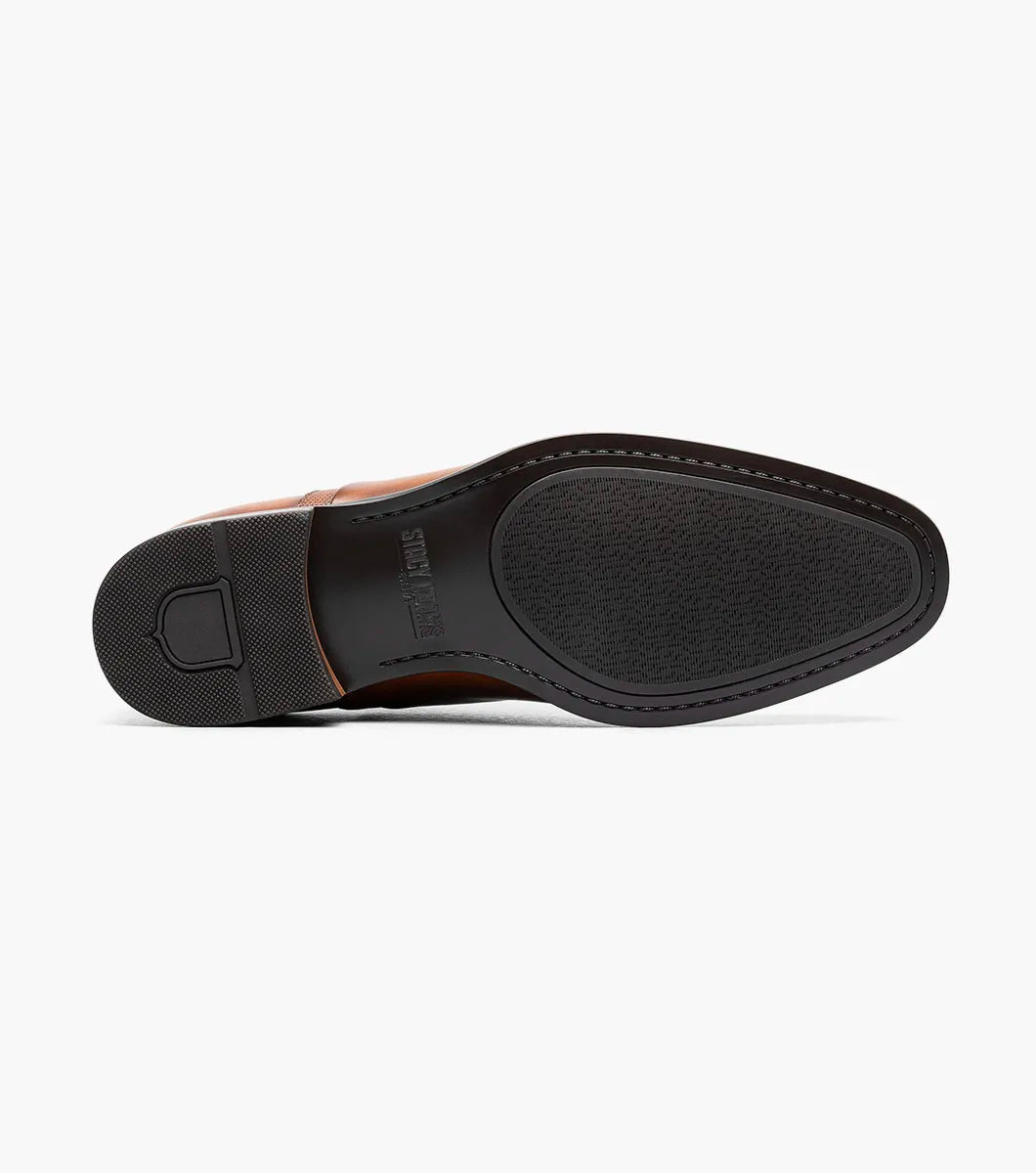 The Stacy Adams Lucas Cap Toe Oxford in Cognac (25766-221) features a brown leather upper with textured side panels, lace-up closure, and low stacked heel for stylish comfort. Men's dress shoe shown on a white background.