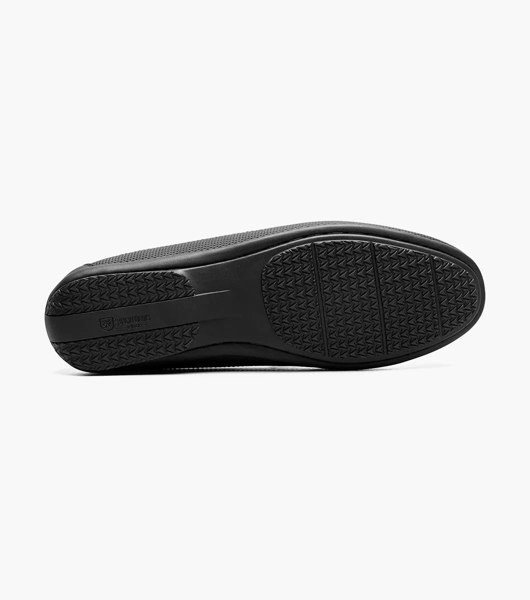 The STACY ADAMS Colton Moc Toe Bit Slip On in black (25760-001) features textured leather, cushioned footbed, metal bit accent, and striped inner lining, shown on a white background.