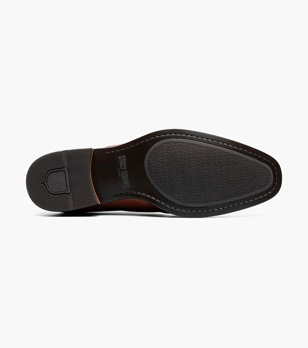 The Stacy Adams Lockwood Wingtip Ornament Slip On in Cognac features classic leather style with a textured upper, single side buckle, and low stacked heel—perfect for men seeking timeless dress shoes.