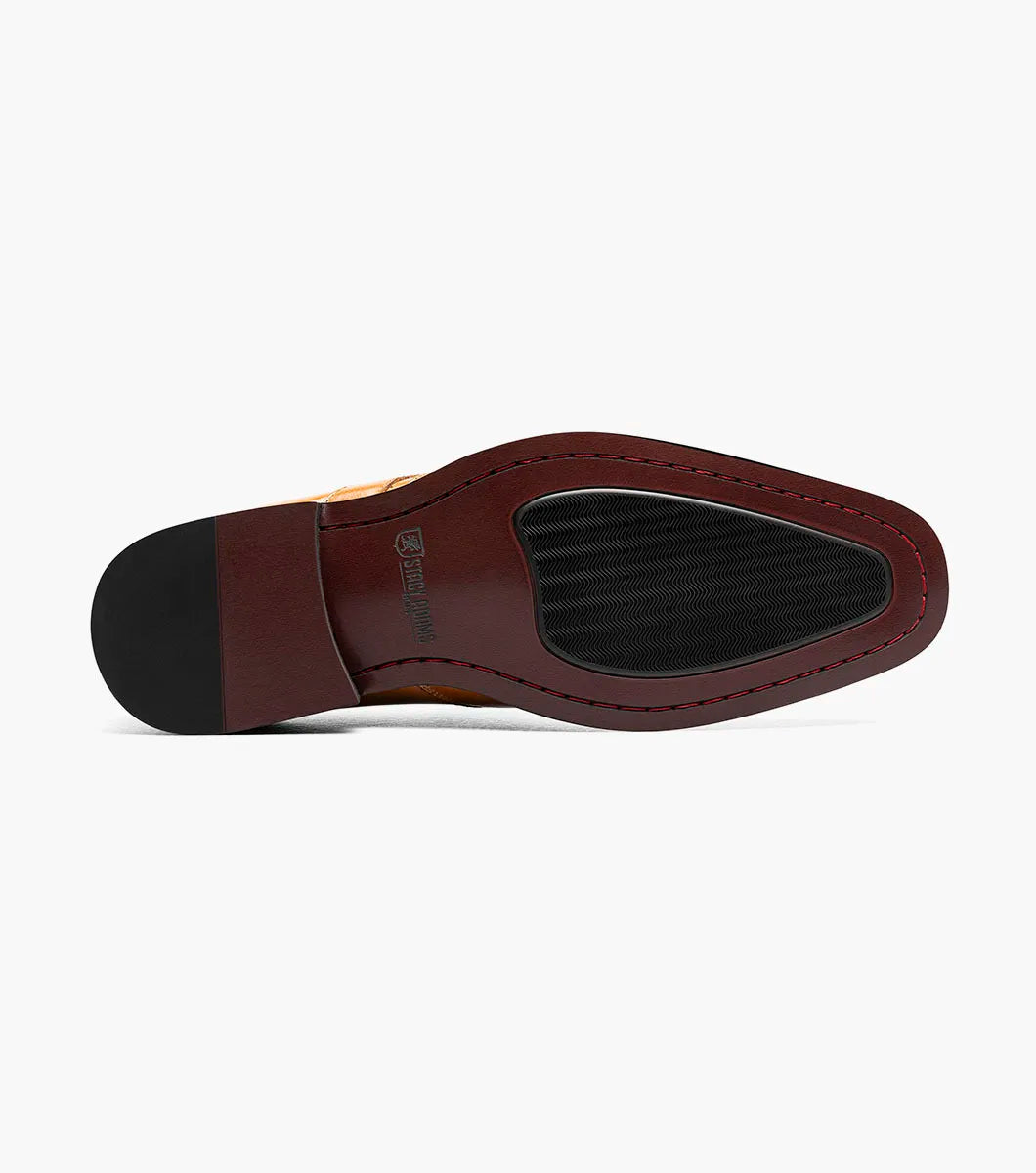 The Stacy Adams Alistair Plain Toe Ornament Slip On (Tan, 25792-240) by STACY ADAMS is a single tan calf leather dress shoe with a pointed toe, decorative perforations, and a side buckle, featuring a comfortable memory foam insole, displayed on a white background.