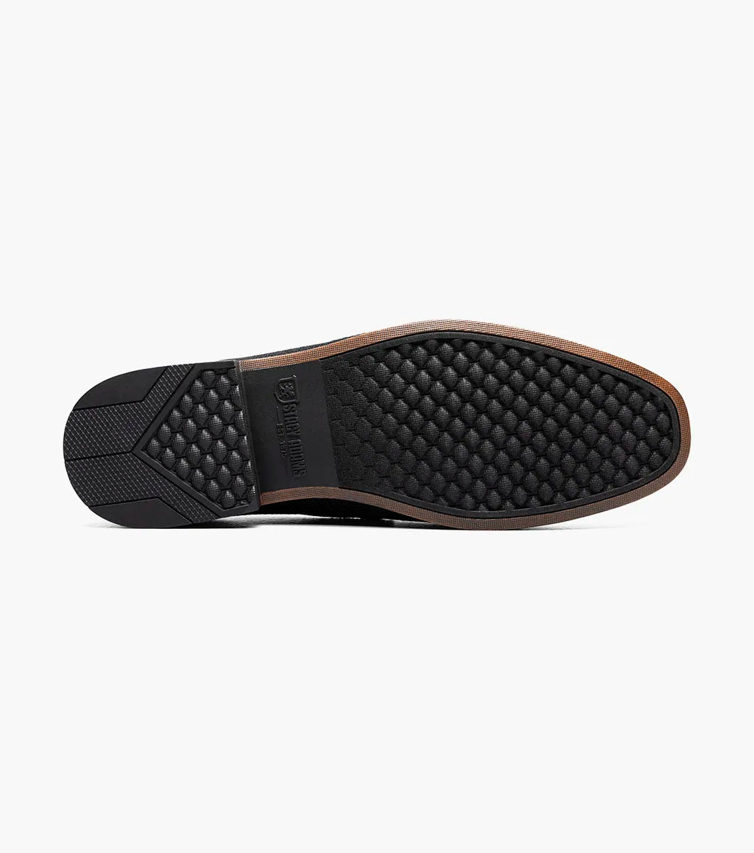 The Stacy Adams Ridgely Moc Toe Slip On in charcoal features visible stitching, a low wooden heel, comfy footbed, and tan lining. Shown against a white background, this casual loafer is perfect for everyday wear.