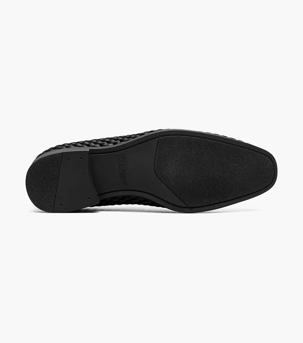 The STACY ADAMS Swenson Woven Slip On in black (25697-001) is a woven leather loafer featuring a low heel and cushioned insole, shown against a white background.