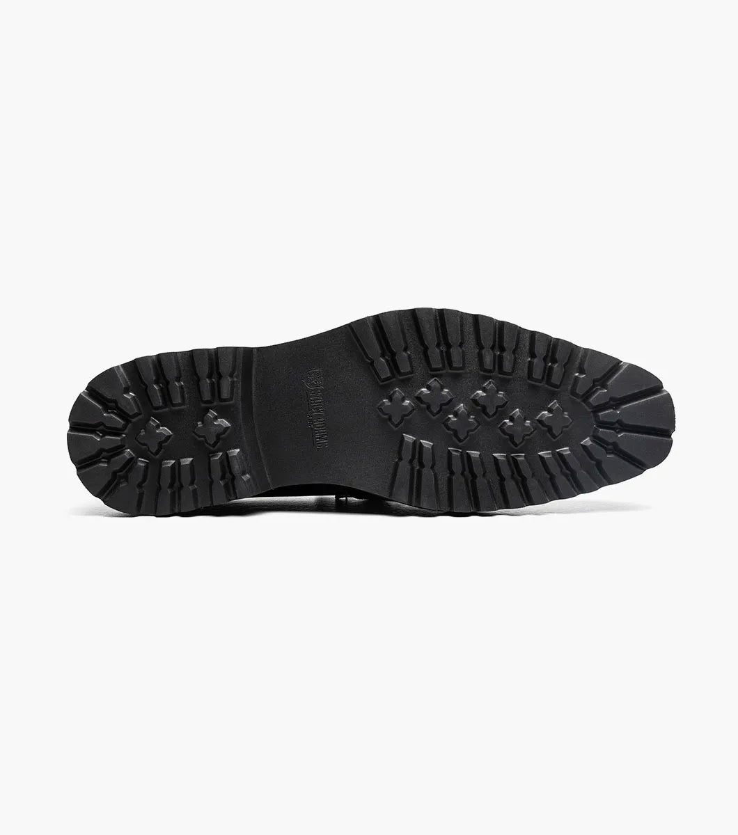 The STACY ADAMS Carabello Moc Toe Bit Slip On (Black Patent, style 25804-004) features a glossy black patent leather upper, a chunky rubber sole, and a sleek metallic bit detail across the front. Designed with a cushioned insole for added comfort, this effortlessly stylish dress shoe is displayed against a white background.