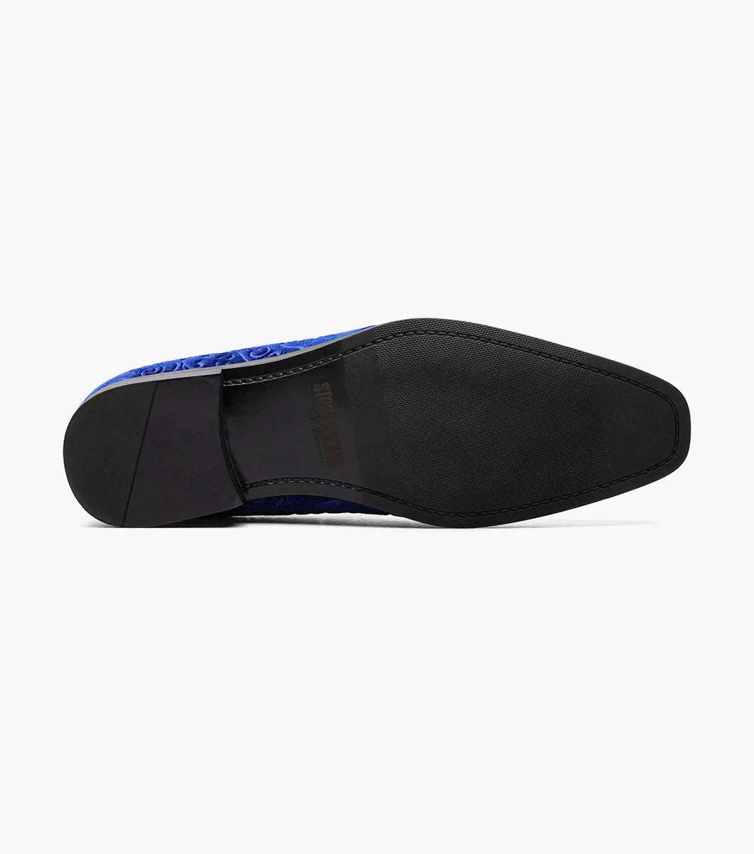The STACY ADAMS Saunders Debossed Velour Slip On in Royal features a blue velour upper, low heel, intricate swirl embroidery, and a memory foam footbed. Shown in side profile against a white background. Style number: 25581-432.