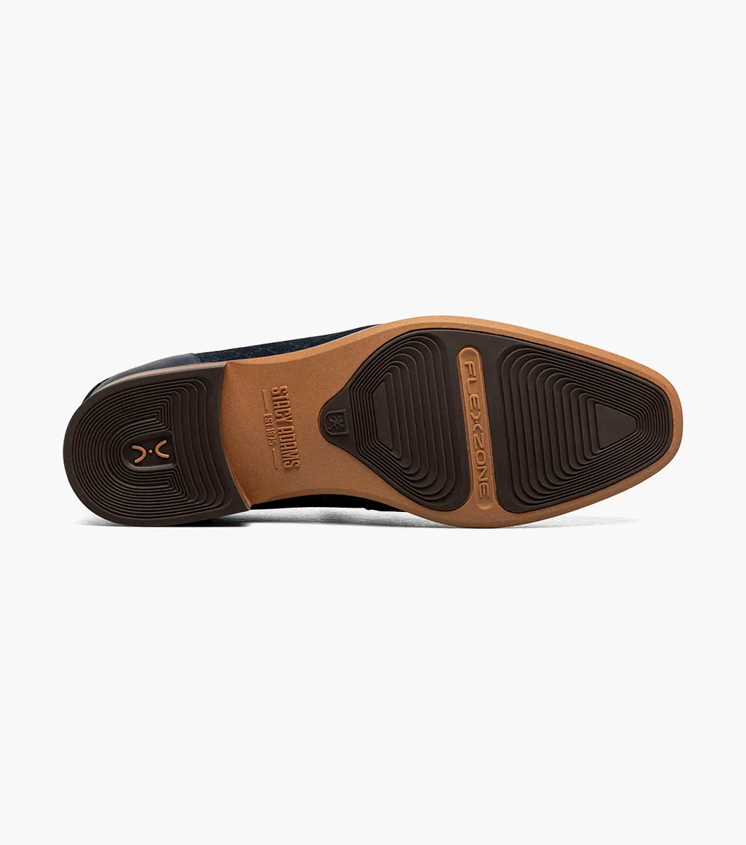 The STACY ADAMS Brinkley Moc Toe Bit Slip On (Navy, 25711-410) features a dark blue suede upper, gold horsebit detail, leather trim, and wooden sole, displayed against a plain white background.