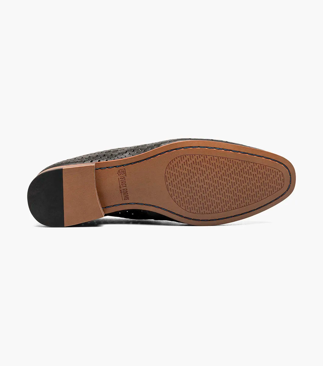 The STACY ADAMS Winden Moc Toe Perf Slip On (Black, 25645-001) features a perforated leather design, memory foam insole for comfort, low heel, and brown sole, shown on a white background.