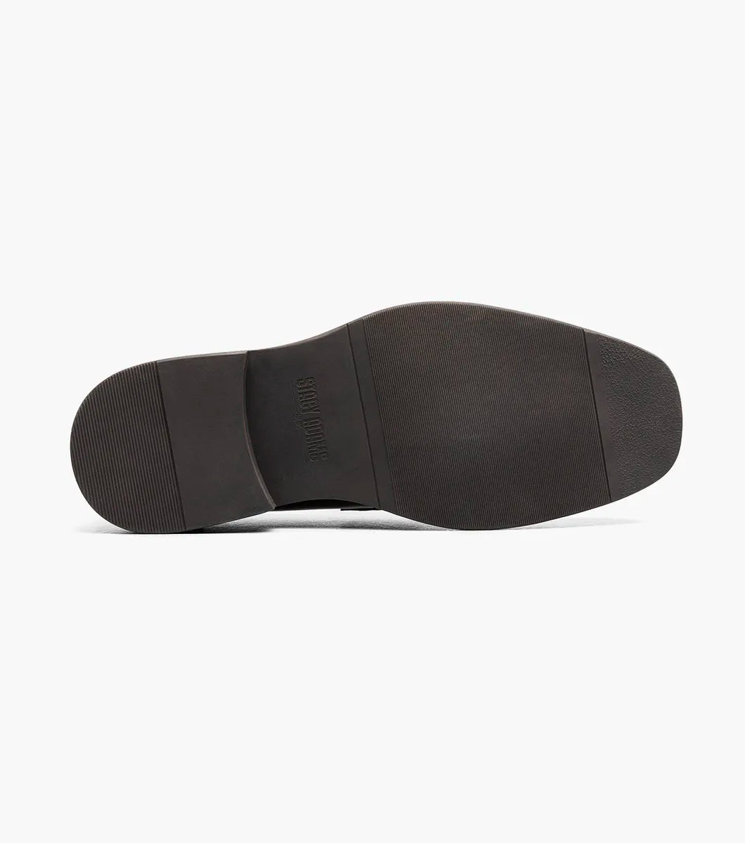 The STACY ADAMS Everett Moc Toe Penny Slip On in brown (style 25790-200) features a classic moc toe design with stitching details, a low heel, a rounded toe, and cushioned comfort from its memory foam insole, shown here against a plain white background.