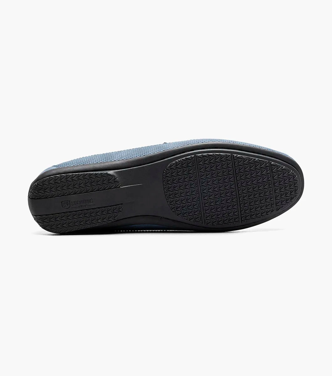 The STACY ADAMS Colton Moc Toe Bit Slip On (Navy, 25760-410) features a cushioned footbed, metal bit detail, moc toe stitching, and a flat black sole, shown on a white background.