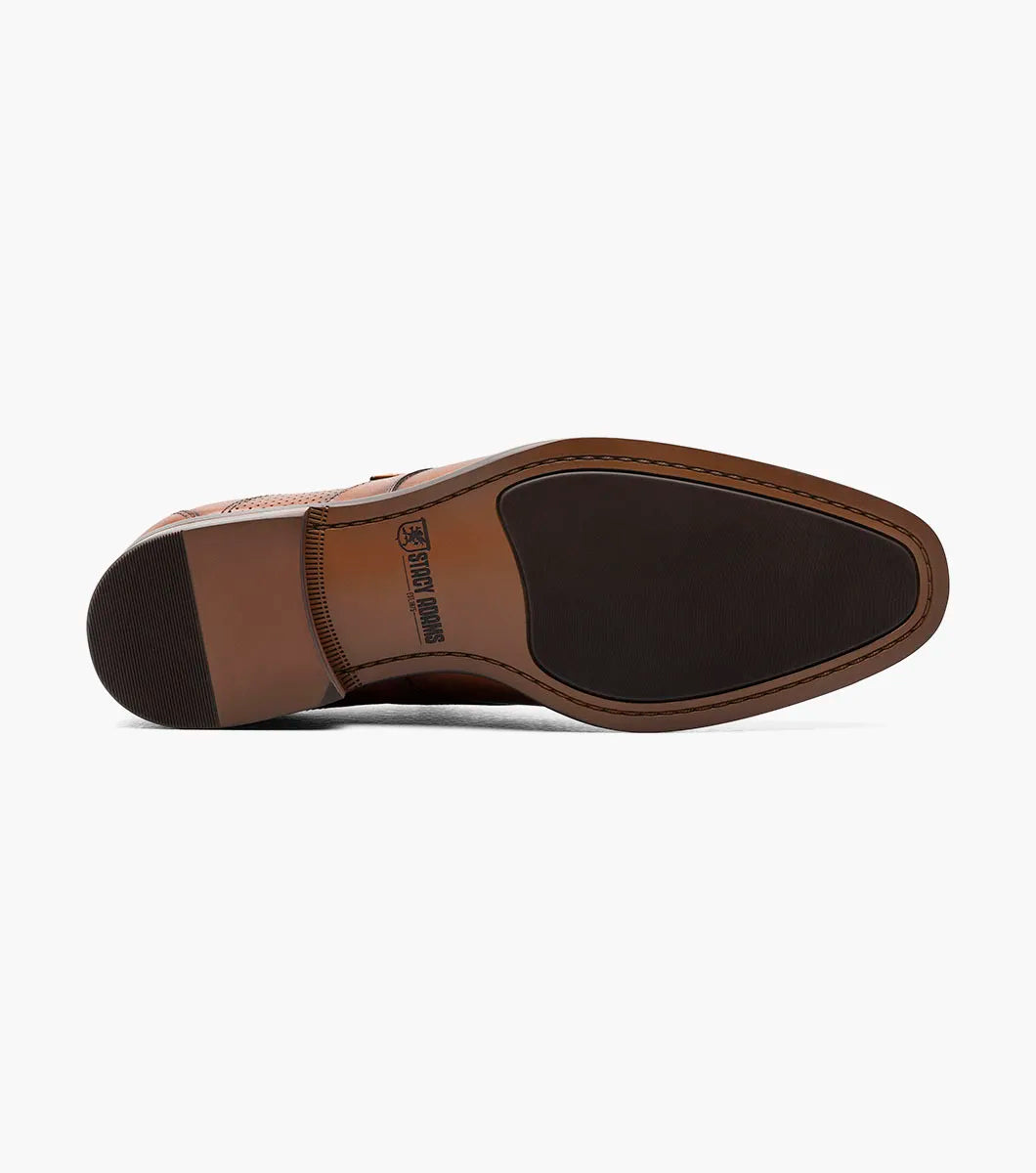 The Stacy Adams Karcher Plain Toe Monk Strap in cognac features a brown leather upper, silver buckle, durable rubber sole, subtle stitching, and low heel. Displayed on a white background. Model: 25590-221. Brand: STACY ADAMS.