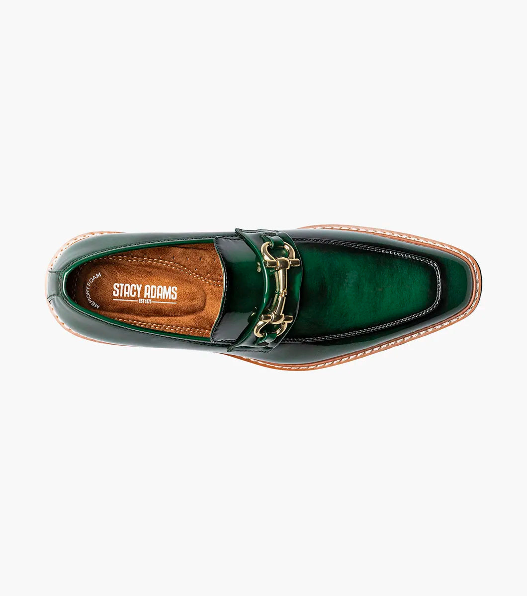 The STACY ADAMS Carabello Moc Toe Bit Slip On in green (style 25804-300) is featured against a white background. This men’s loafer showcases glossy green leather, a gold-tone bit detail, tan stitching, and a thick black lug sole for a sophisticated yet striking look that blends timeless style with modern flair.