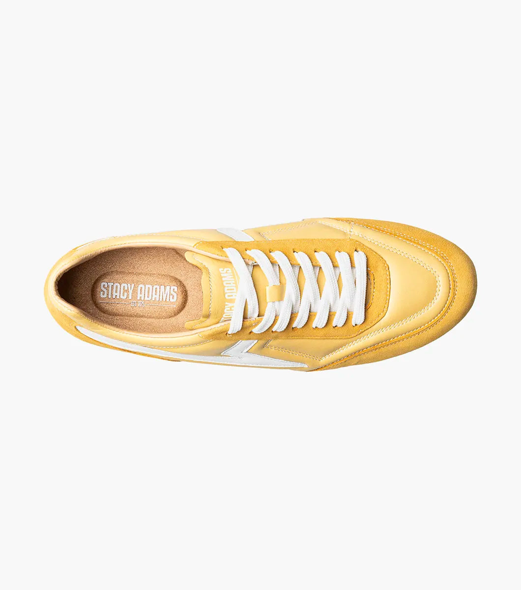Introducing the Stacy Adams Action 150 Sporty Lace Up sneaker in yellow (Style 25797-700) by STACY ADAMS. This modern shoe features white laces, a white zigzag stripe on the side, tan lining, and a flat white sole. Angled to display both the side and front, it showcases its contemporary design and cushioned footbed for all-day comfort.