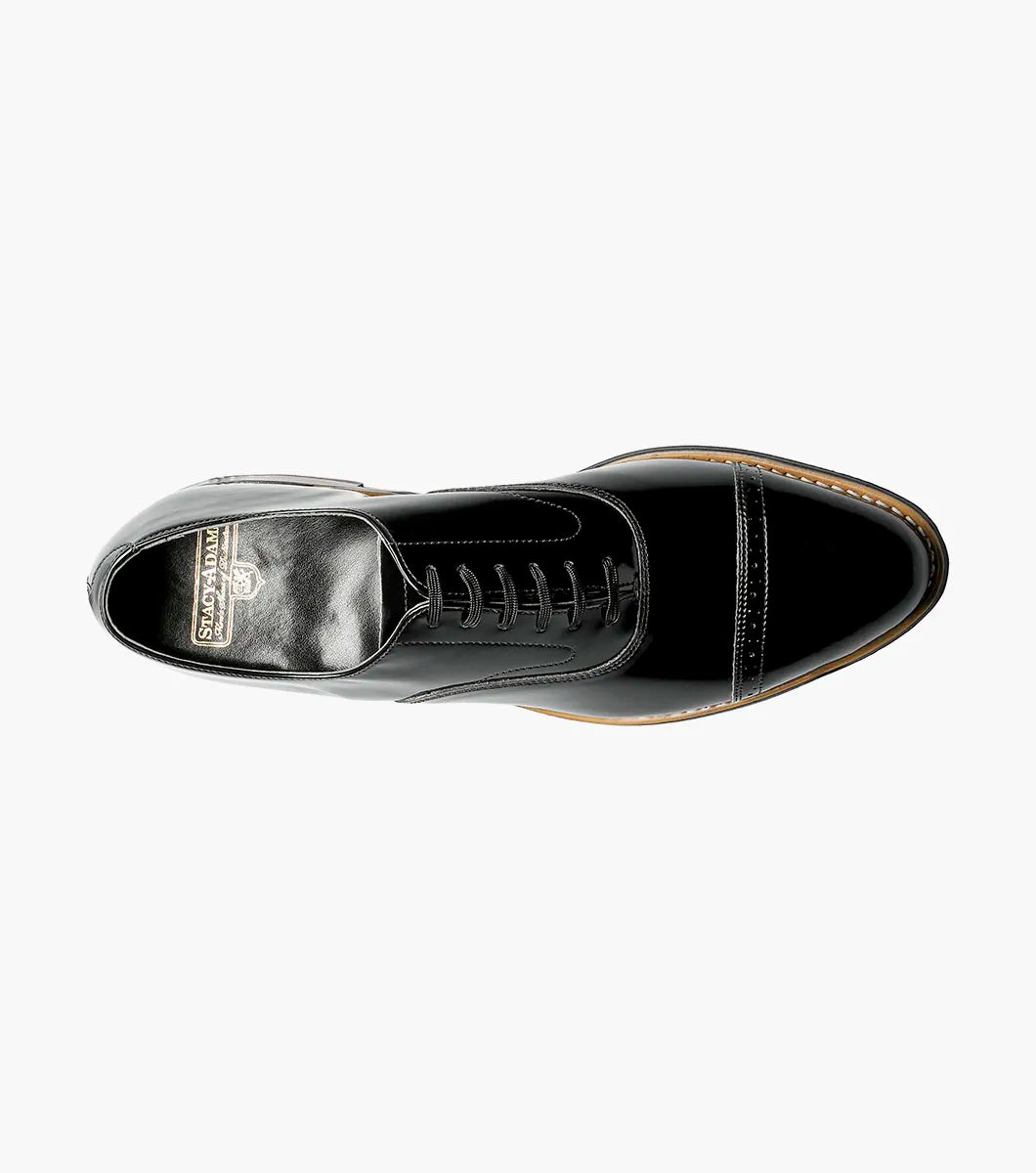 The Stacy Adams Concorde Cap Toe Oxford (Style 11003-01) features a black patent leather upper, cap toe, black laces, low heel, and stitching detail. Shown in side profile against a white background. Brand: STACY ADAMS.