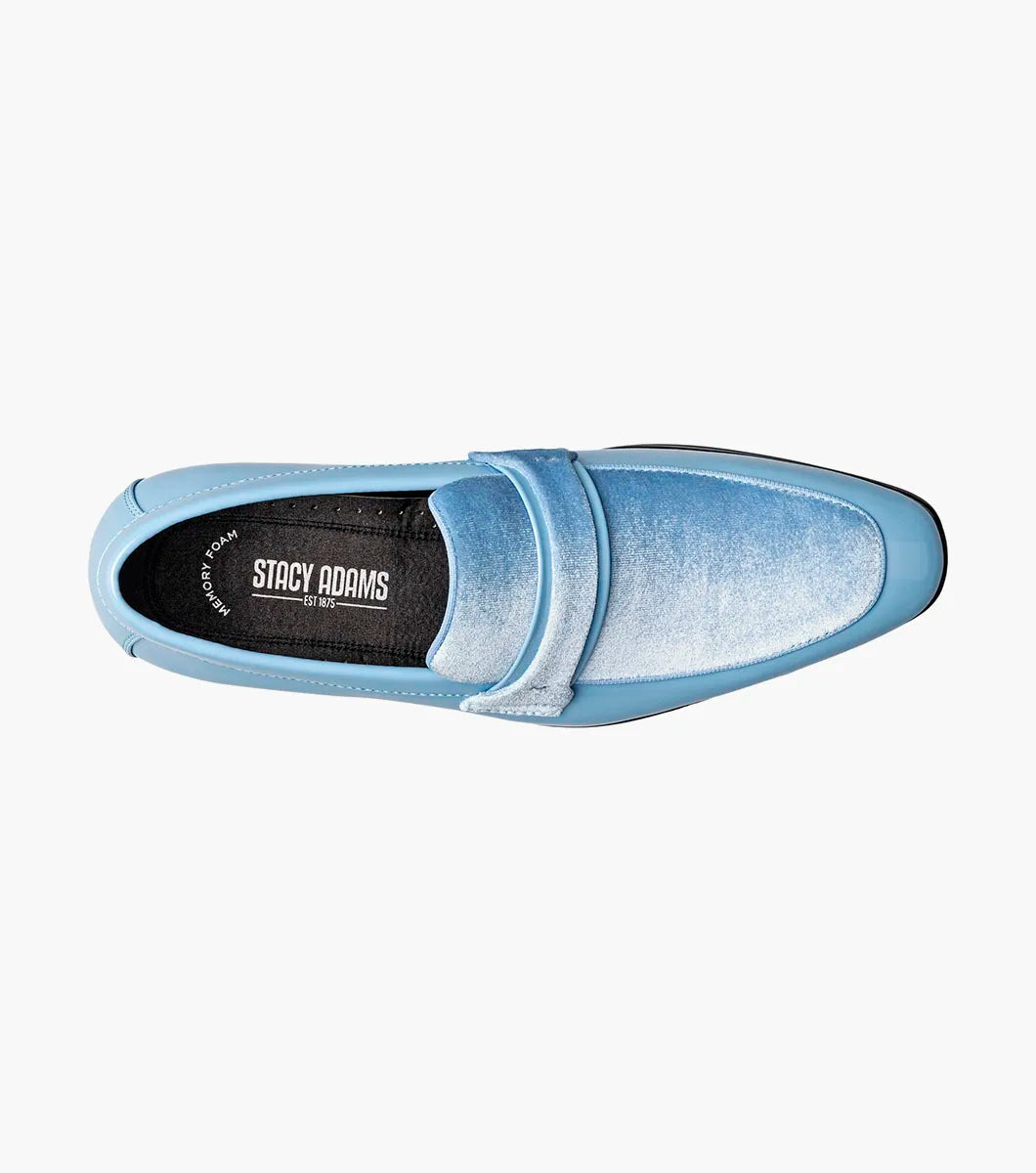 The Stacy Adams Spratley Moc Toe Saddle Slip On in light blue (style 25686-459) showcases a glossy patent leather body with a velour upper, complemented by a matching suede strap and vamp. This men’s loafer by STACY ADAMS features a cushioned insole for enhanced comfort, a black sole, and a low heel, all presented against a plain white background.