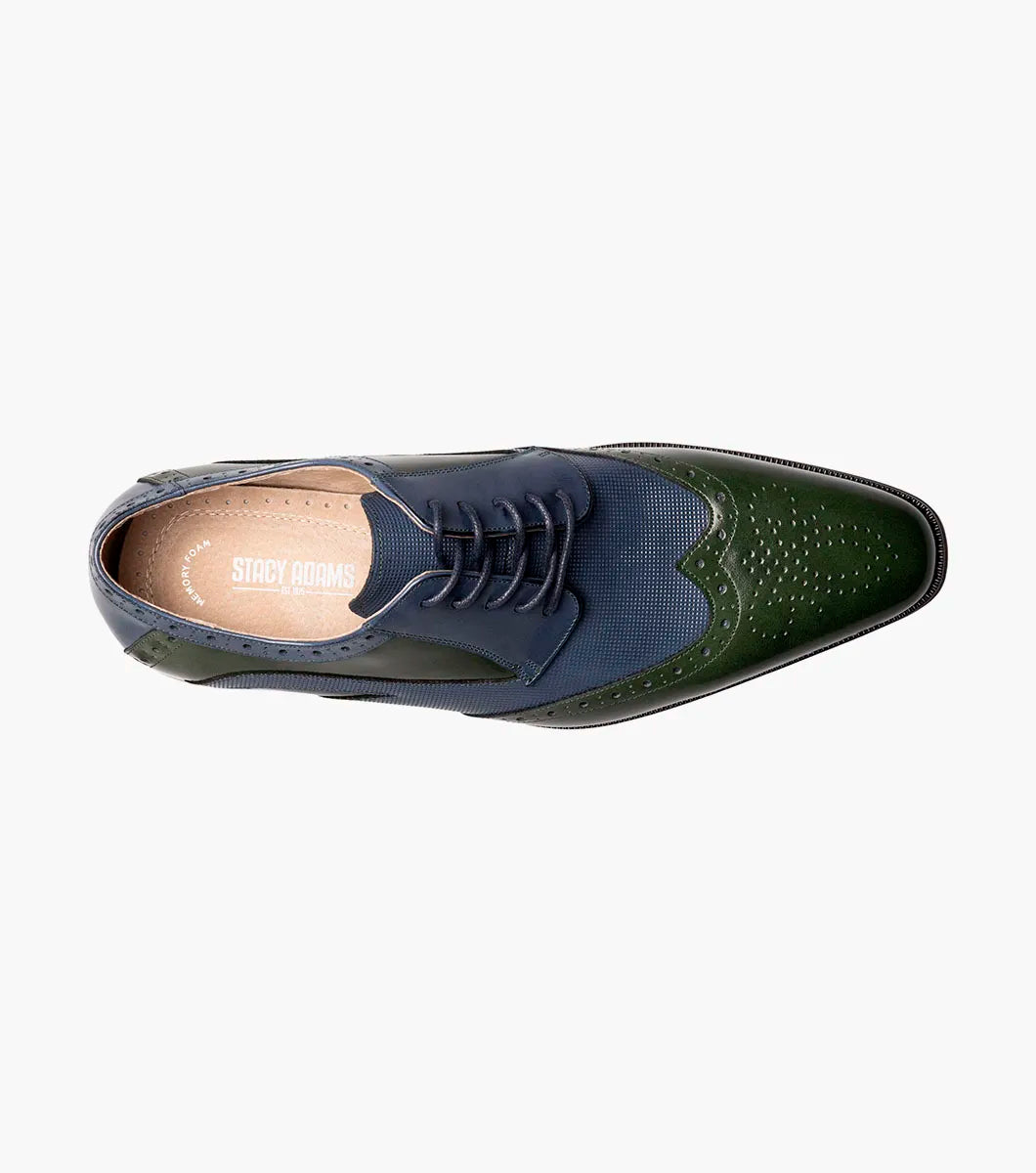 The STACY ADAMS Ivingale Wingtip Oxford (25684-411) is a men's dress shoe in navy and green leather with brogue details, closed lacing, and a black sole, shown on a white background.